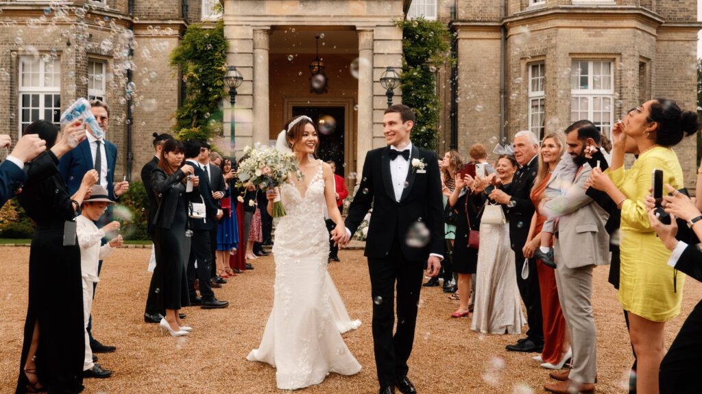 Bride and groom, Estelle and Augustin, share a romantic moment in front of Hedsor House's grand facade during their elegant wedding.