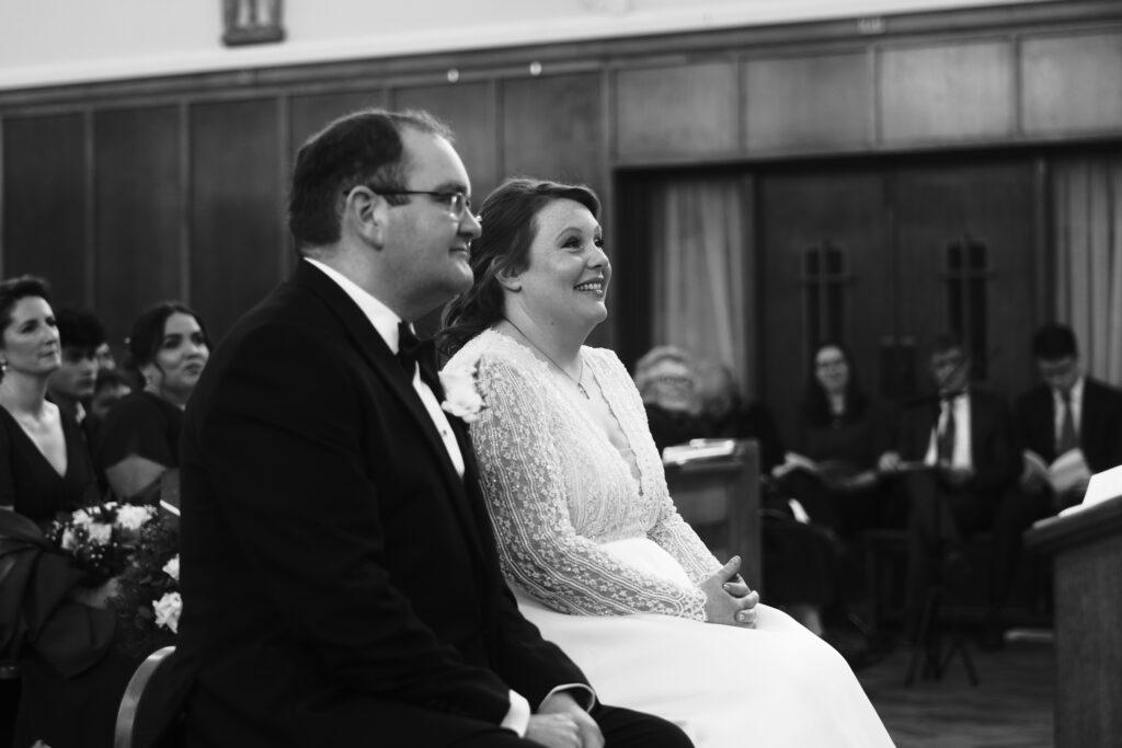 The bride and groom are all smiles in the church as the priest conducts his sermon. This photo was captured as part of a premium wedding content creation package.