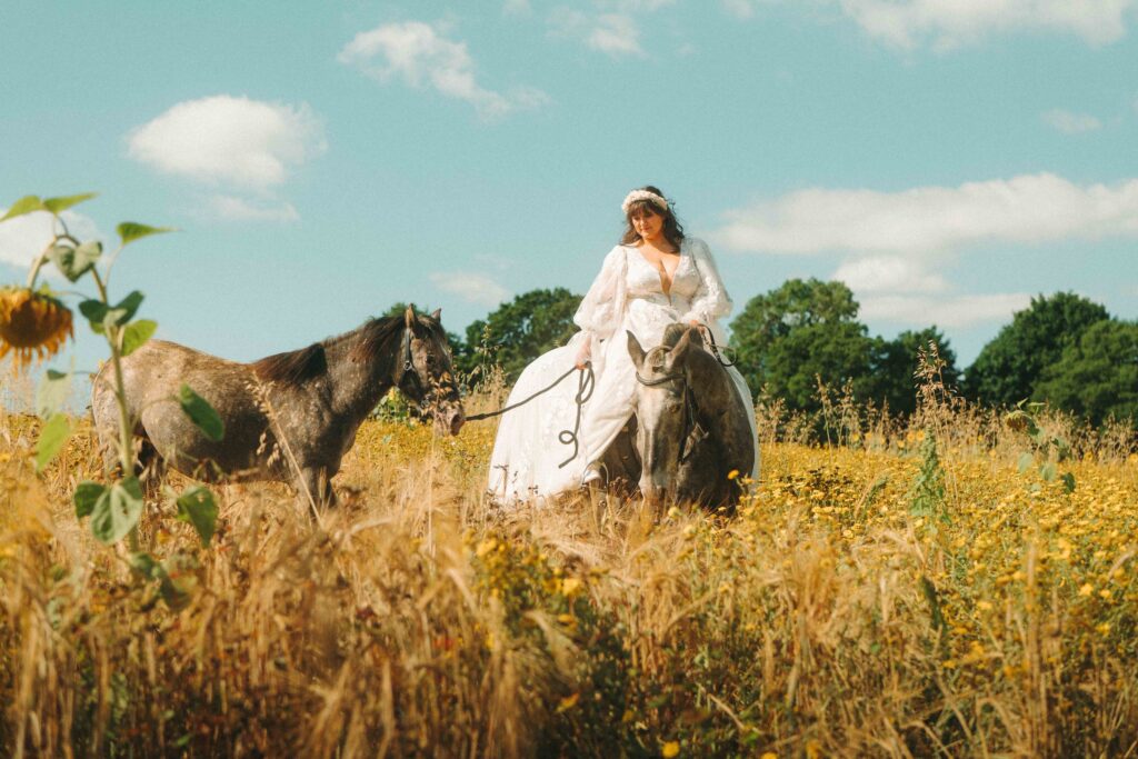 A bride on horseback on her wedding day in the Cotswolds. This bride was keen to include her horses in her wedding film, dress be damned! 