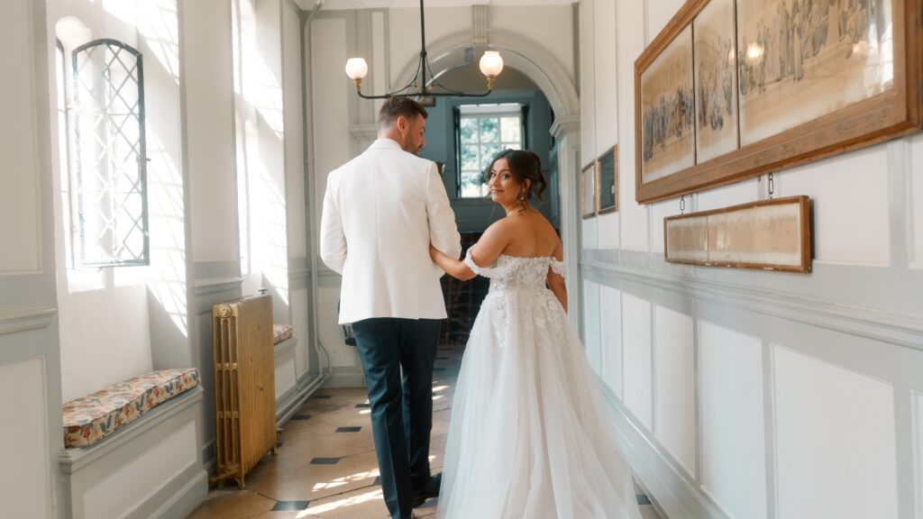 A bride and groom take a stroll on their wedding day down the corridors of Gosfield Hall. Captured on film by Wedding Videographer Scott from HC Visuals. 